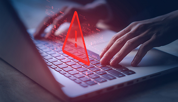 Image of a person on a computer with a cybersecurity warning.