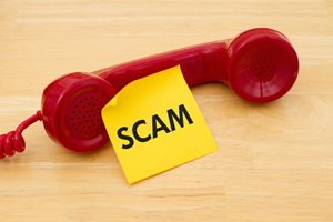 Telephone with a sticky note saying "scam"
