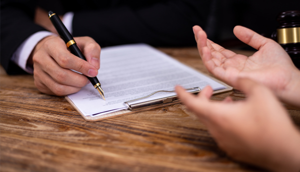 Person writing on paper on a clipboard